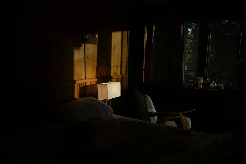 Een schemerige kamer in de avond met een lamp en een raam